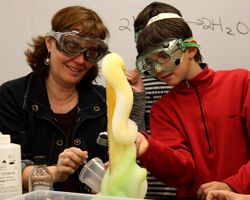 A teacher and a student doing the elephant's toothpaste experiment in a classroom setting.