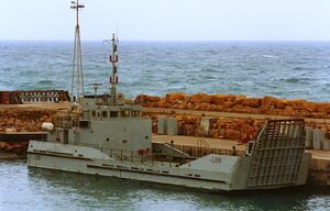 Image of small landing craft alongside harbour wall.