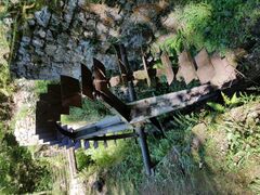 Photograph of an abandoned water wheel near a hiking path.