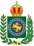 Coat of arms consisting of a shield with a green field with a golden armillary sphere superimposed on the red and white Cross of the Order of Christ, surrounded by a blue band with 20 silver stars; the bearers are two arms of a wreath, with a coffee branch on the left and a flowering tobacco branch on the right; and above the shield is an arched golden and jeweled crown.