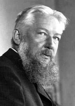 A black and white portrait of Ostwald with long, white beard, wearing a dark coloured mantle over a white shirt. Ostwald is facing to the right with his head slightly turned towards the camera.