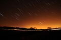 Short streaks of light on a dark sky, showing star trails that were photographed with a long exposure.