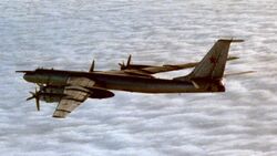 A four-engine prop-driven aircraft flying above white clouds