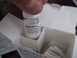 A small vial with writing on it being removed from a cardboard package