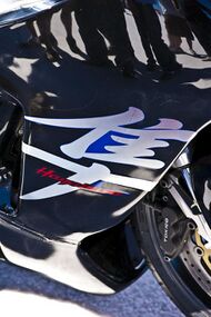The side of the bodywork of a sport motorcycle with the legend Hayabusa superimposed on a Japanese character 隼.