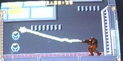 A video game screenshot of a person in a powered exoskeleton firing a beam.