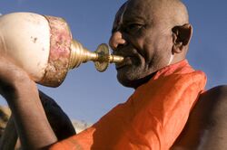 Hindu priest blowing conch during punja.jpg