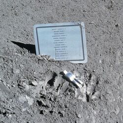 A small aluminum statue and a plaque on the lunar surface