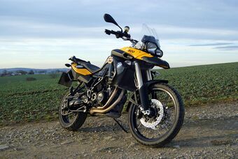 Black and yellow motorcycle parked on the edge of a field