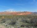 A photo of the Red Cliffs with snow-capped Pine Valley Mountains in the background