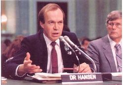 James Hansen speaking into a microphone while seated in Congress.