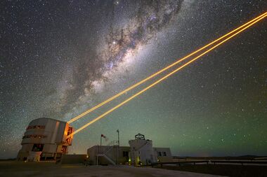 A telescope emitting four orange laser beams.
