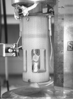 The sample assembly for a resonance ultrasonic spectroscopy measurement showing the sample cube lightly held between the two buffer rods that transmit the ultrasonic excitations between the transducers and the cube.