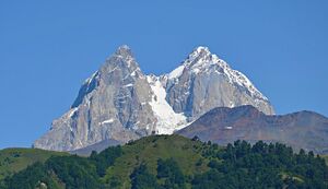 A double-peaked, snow-covered mountain under cloudless blue sky