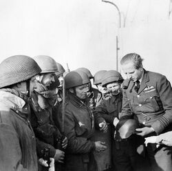 Wing Commander Percy Pickard, CO of No. 51 Squadron RAF, inspects a captured German helmet with troops from 2nd Parachute Battalion after the Bruneval raid, 28 February 1942. H17347.jpg