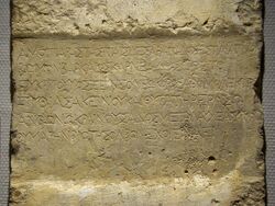 Large square marble slab that has been engraved. The inscription states: "Beside these walls of Serapis the warden of the temple Karneades of Barke, son of Eukritos, o foreigner, and his spouse Pythias and his daughter Eraso placed to Hestia a pure altar, as a reward for this, o you that governs the marvelous dwellings of Zeus, grant to them a lovely auspiciousness of life."