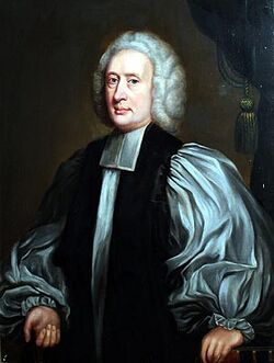A middle-aged white man seated and wearing Georgian-era English clerical robes.