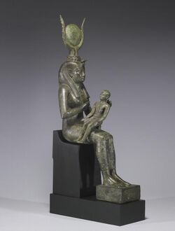 Small statue of a seated woman, with a headdress of horns and a disk, holding an infant across her lap