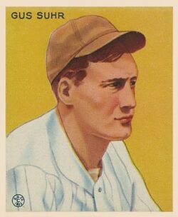 An old baseball card showing a man wearing a brown cap and white uniform looking to the right on a yellow background. Capital letters in the upper left identify him as Gus Suhr