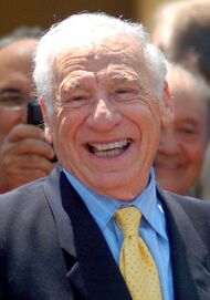 A smiling light-skinned elder man in a suit.