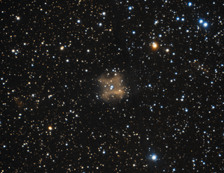 fuzzy orange shape in the center of a field of point-like star glows against a black background