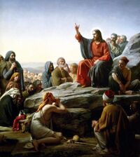 Jesus sits atop a mount, preaching to a crowd