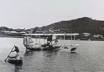 Single-engined military biplane on floats in harbour