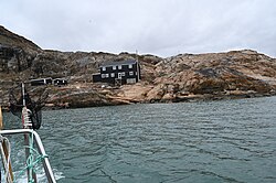 A two story building in black seen from the sea