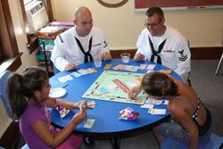 US Navy 110713-N-NT881-124 Personnel Specialist 2nd Class James Vail, left, and Boatswain's Mate 2nd Class Nathaniel Eaton play board games with ch.jpg