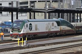 A white diesel locomotive with a dark brown underside and dark green roof