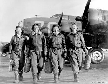 Four female pilots walking toward the camera away from a large aircraft