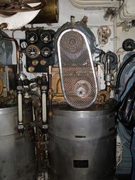 The vapour-compression distiller installed in the submarine's engine room. A cylindrical drum water vessel carries the compressor and its electric motor with belt drive above it.