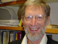 The head of a smiling, bespectacled and bearded man in his seventies.