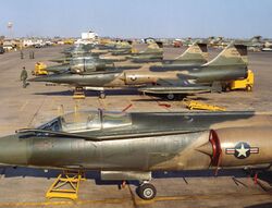 Row of numerous F-104 aircraft parked on display on airport apron