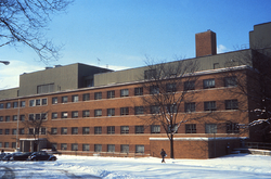 Photograph of a large five-story brick building with snow on the ground around it