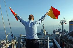 US Navy 051129-N-0685C-007 Quartermaster Seaman Ryan Ruona signals with semaphore flags during a replenishment at sea.jpg