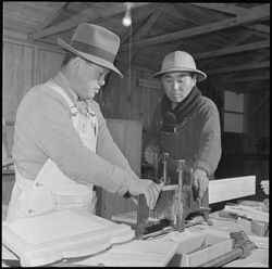 Photo of two incarcerated Japanese Americans using an adjustable mitre box.