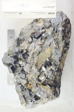 A black and silver-coloured rock with protruding crystals appearing with 4, 5 and 6 sides