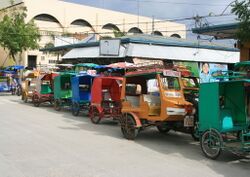 Motor tricycles for hire lined up outside public market in downtown Bantayan.JPG