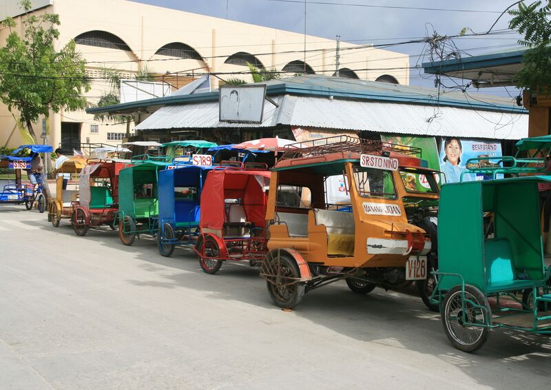 File:Motor tricycles for hire lined up outside public market in downtown Bantayan.JPG