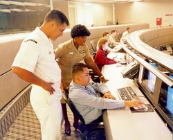 US Navy 040614-N-7952W-001 Information Systems Technician 1st Class Thomas Dull, left, Lt. Stella Nealy, center, and Information Systems Technician 2nd Class Eduardo Pallanes study a computer monitor at Naval Network and Space.jpg