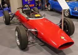Red open cockpit single seat race car with unguarded tyres