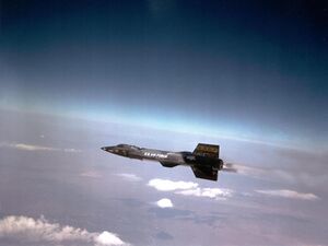 Black rocket aircraft with stubby wings and short vertical stabilizers above and below tail unit
