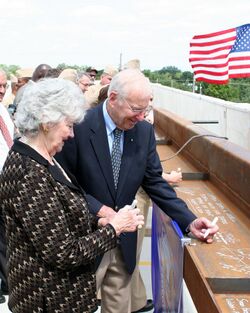 US Navy 090824-N-9876C-013 Retired Navy captain and former astronaut Jim Lovell and his wife, Marilyn Gerlach, sign the final roofing beam to be lifted into place during the topping off ceremony for the Captain James A. Lovell.jpg
