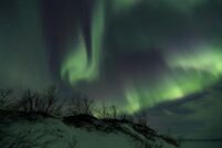 The solar wind moving through the magnetosphere alters the movements of charged particles in the Earth's thermosphere or exosphere, and the resulting ionization of these particles causes them to emit light of varying colour, thus forming auroras near the polar regions.