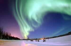 colour photograph of the green aurora borealis over an icy landscape