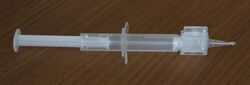 A small plastic disposable syringe with a lens insertion nozzle attached. The nozzle tapers to a small tip through which the foldable lens is expressed into the posterior capsule, and can fit into a 2.8mm wide incision.