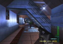 A long corridor with columns and girders on the right side. An opponent is standing in the distance. A hand holding a weapon and graphics symbols representing ammunition are seen at the bottom right corner.