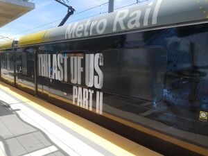 A train with an advertisement for the game: the large block text says "The Last of Us Part II", with a dark picture of Ellie's face.