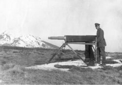 Soldier standing next to a Telescopic instrument on a tripod.